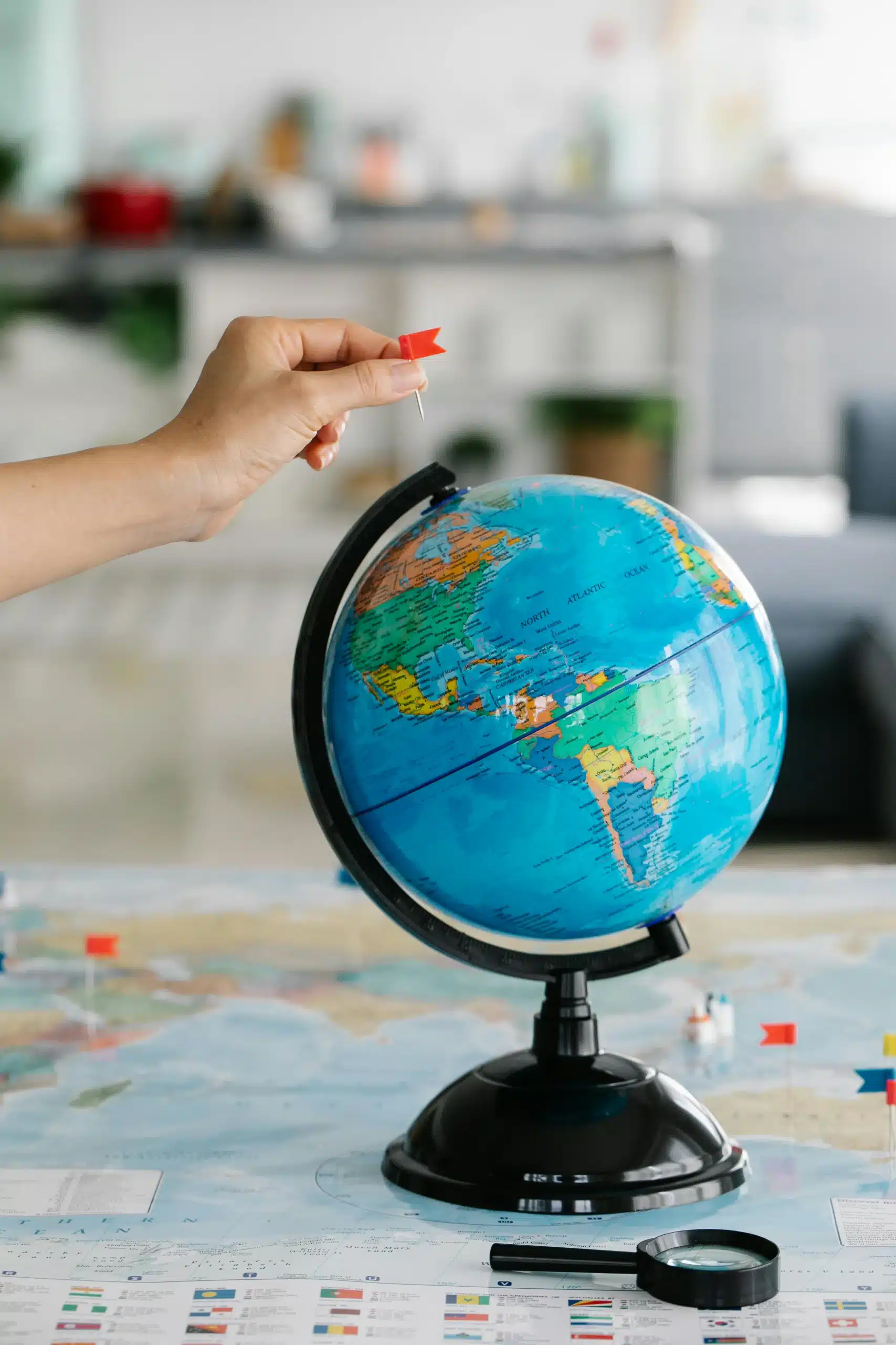 Hand placing a red flag on a world globe representing global multilingual marketing reach