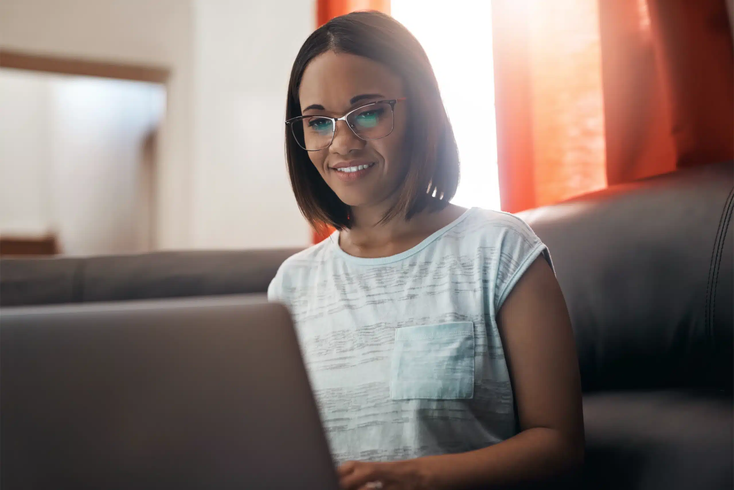 seo-spanish-bilingual-audiences-hispanic-woman A Hispanic woman working on a laptop at home, representing how businesses can reach bilingual audiences through Spanish-language SEO