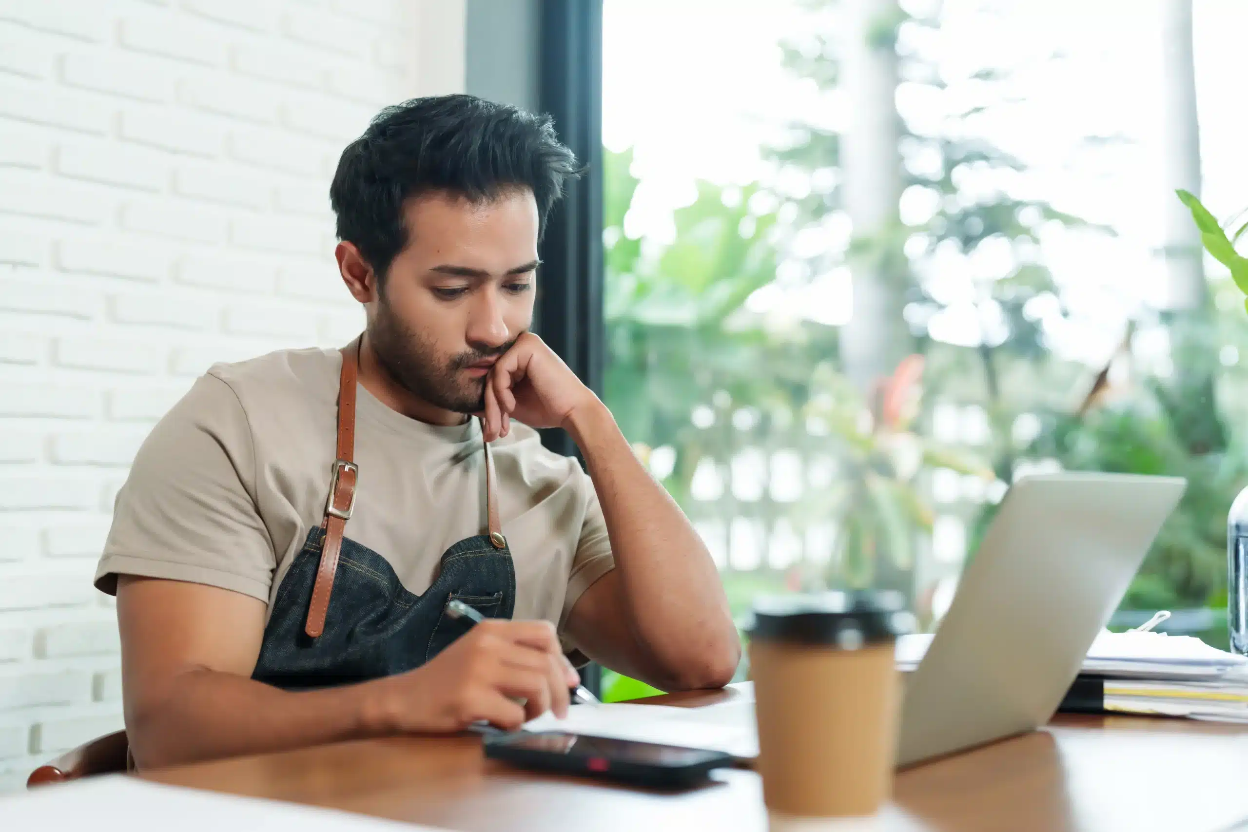 What to post social media creative block A business owner sitting at their desk looking at their laptop, trying to figure out what to post on social media.